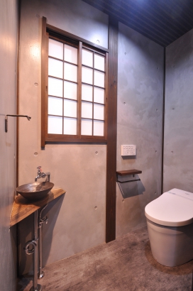 モルタル風塗りの無機質なトイレ。