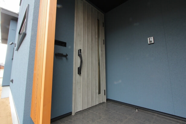 青い外壁に白い玄関ドア